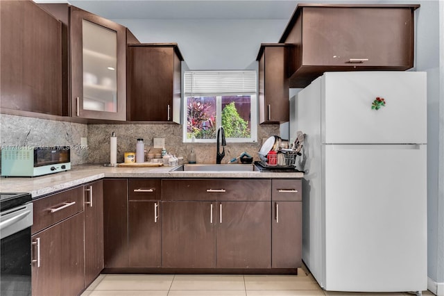 kitchen with white refrigerator, sink, decorative backsplash, dark brown cabinets, and light tile patterned flooring