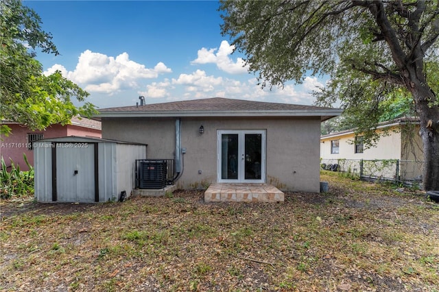 rear view of house with central AC unit, a storage unit, and french doors