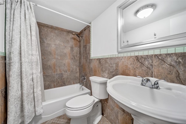 full bathroom featuring toilet, tile walls, shower / bath combo with shower curtain, and sink