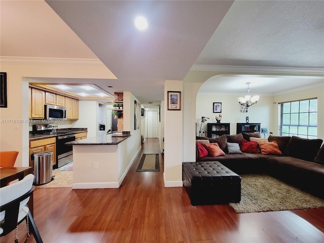 living room featuring sink, an inviting chandelier, light wood-type flooring, and ornamental molding