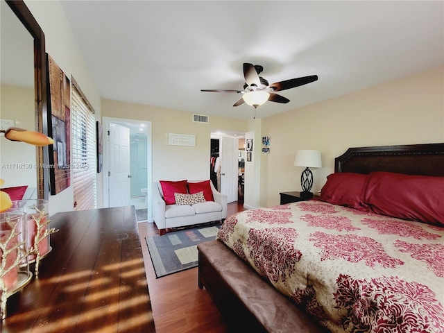 bedroom with a walk in closet, ensuite bath, ceiling fan, wood-type flooring, and a closet