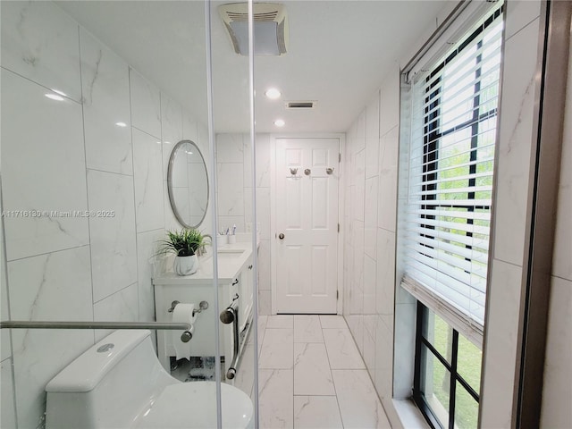 bathroom featuring vanity, tile walls, and toilet