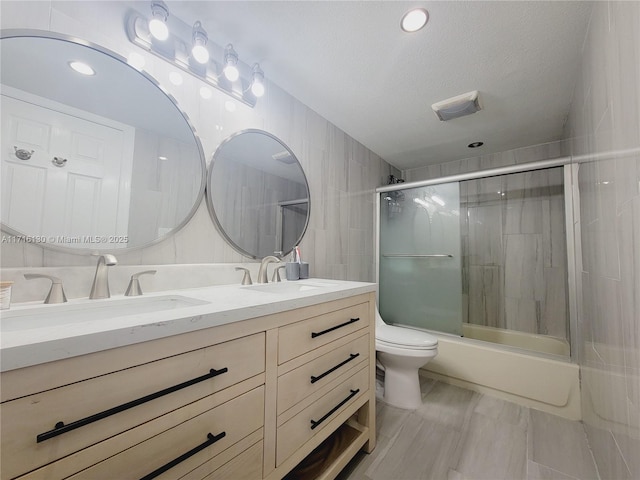 full bathroom featuring vanity, bath / shower combo with glass door, a textured ceiling, and toilet