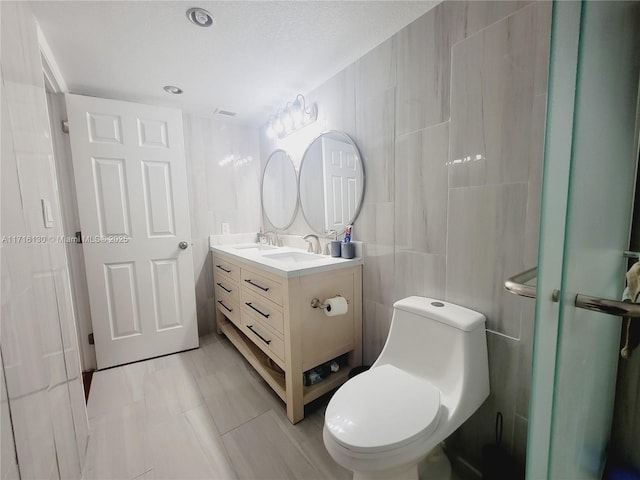 bathroom featuring an enclosed shower, vanity, toilet, and tile walls