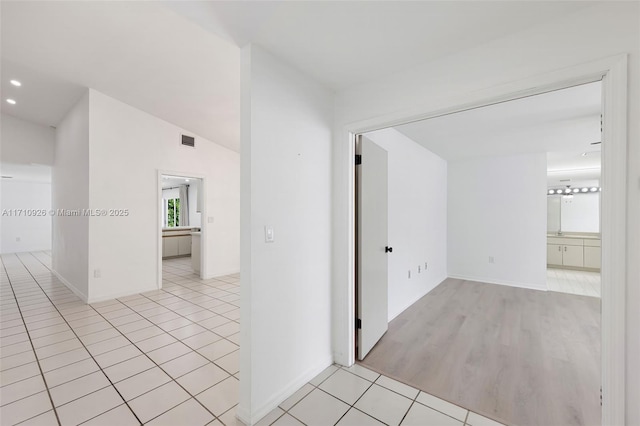 corridor featuring lofted ceiling and light tile patterned floors