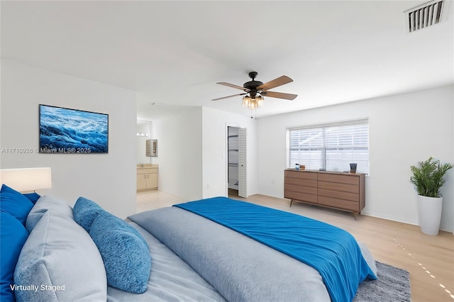 bedroom featuring light wood-type flooring, ceiling fan, and ensuite bathroom