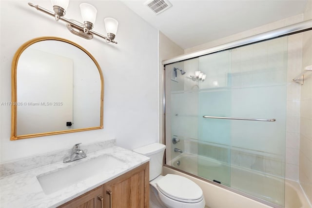 full bathroom featuring vanity, bath / shower combo with glass door, and toilet