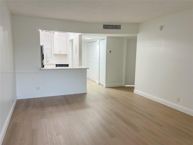 unfurnished room with light hardwood / wood-style flooring and a textured ceiling