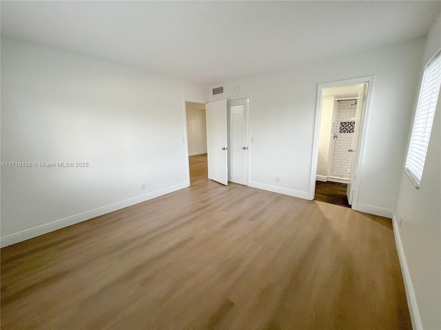 unfurnished bedroom featuring hardwood / wood-style floors and ensuite bathroom