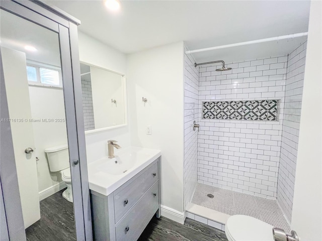 bathroom featuring a tile shower, hardwood / wood-style flooring, and toilet