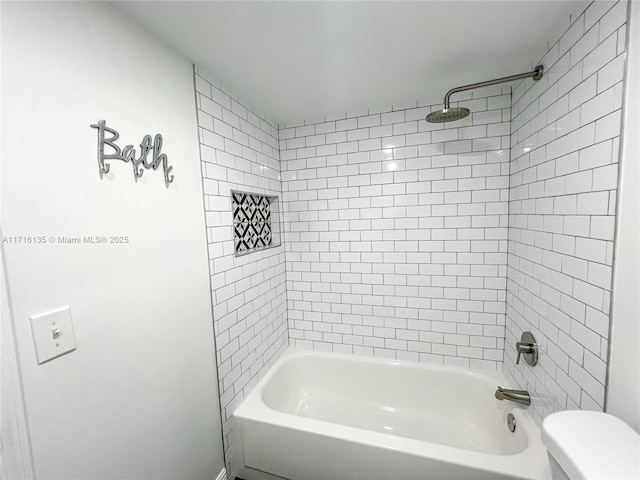 bathroom with toilet and tiled shower / bath