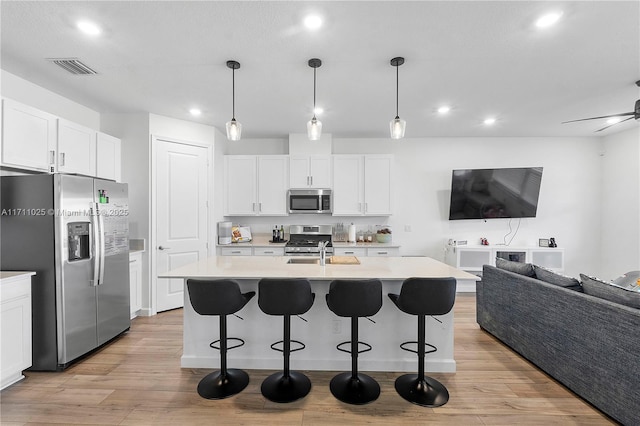 kitchen with white cabinets, stainless steel appliances, and an island with sink