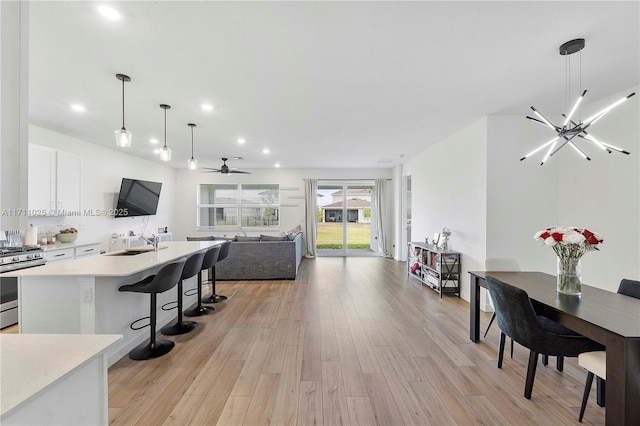 kitchen featuring gas stove, white cabinetry, ceiling fan with notable chandelier, and decorative light fixtures