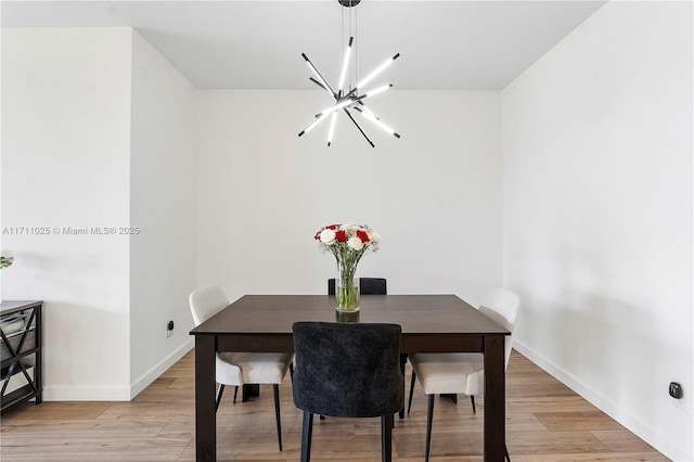 dining space with light hardwood / wood-style flooring and a notable chandelier