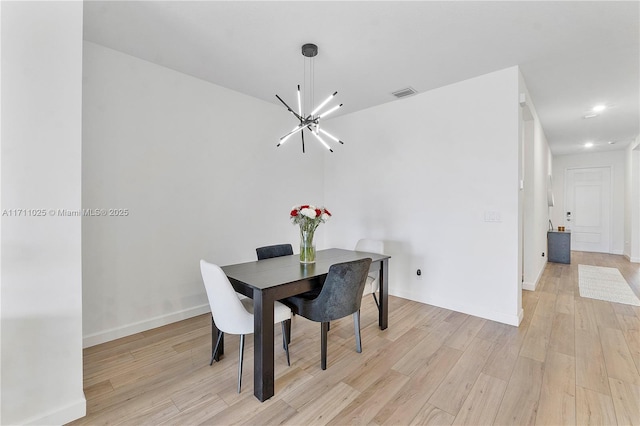 dining room with light hardwood / wood-style floors and an inviting chandelier