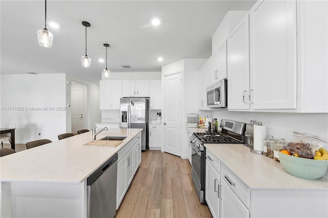 kitchen featuring white cabinetry, sink, hanging light fixtures, an island with sink, and appliances with stainless steel finishes