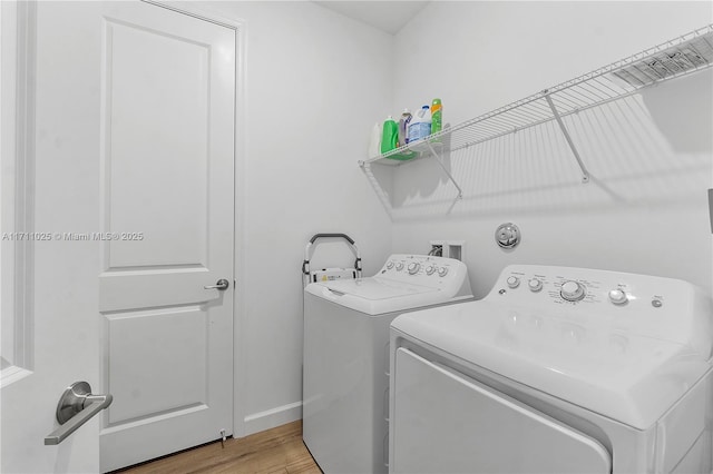 laundry area with separate washer and dryer and light hardwood / wood-style floors