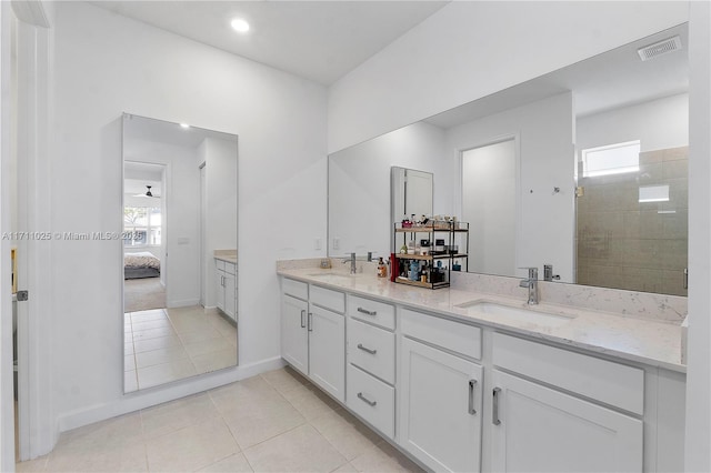 bathroom with tile patterned flooring, vanity, and a tile shower