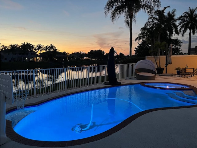 pool at dusk featuring an in ground hot tub and a patio