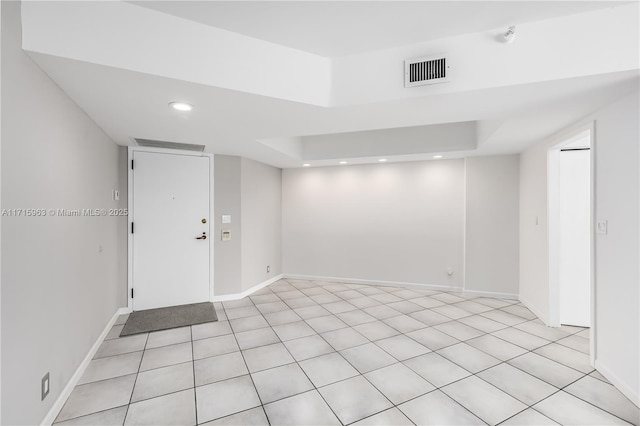 spare room featuring a raised ceiling and light tile patterned floors