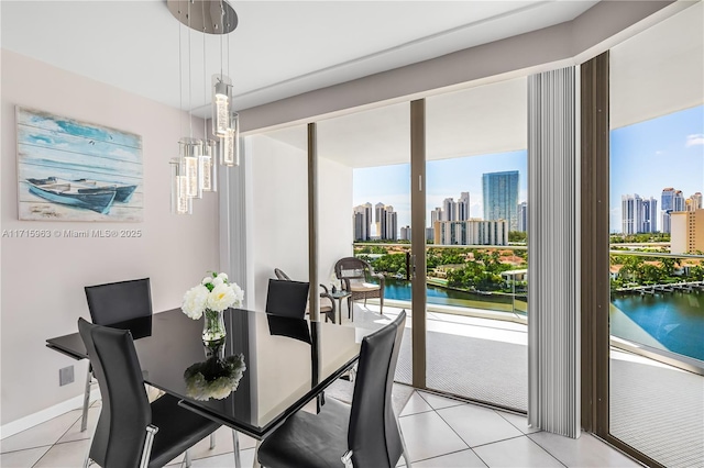 dining area with a wealth of natural light, a water view, and light tile patterned flooring