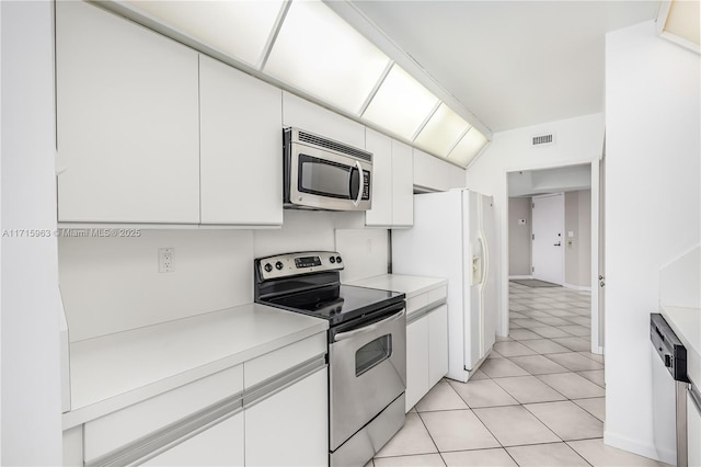 kitchen featuring white cabinets, light tile patterned floors, stainless steel appliances, and lofted ceiling