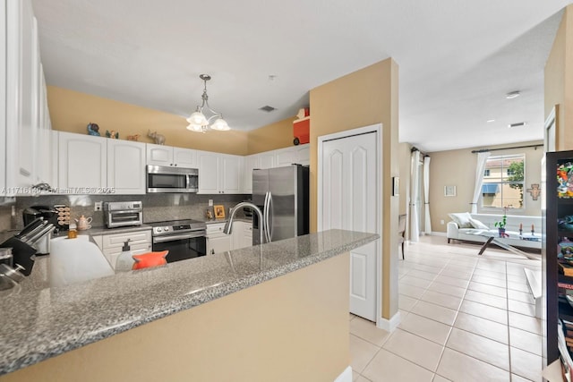 kitchen featuring kitchen peninsula, appliances with stainless steel finishes, white cabinets, and hanging light fixtures