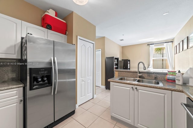 kitchen featuring stainless steel refrigerator with ice dispenser, light tile patterned floors, white cabinetry, and sink