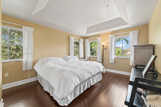 bedroom with a raised ceiling, dark hardwood / wood-style flooring, and a textured ceiling