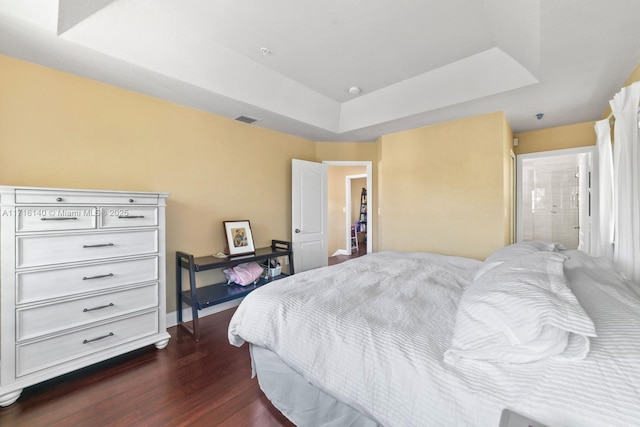 bedroom featuring dark hardwood / wood-style flooring and a raised ceiling