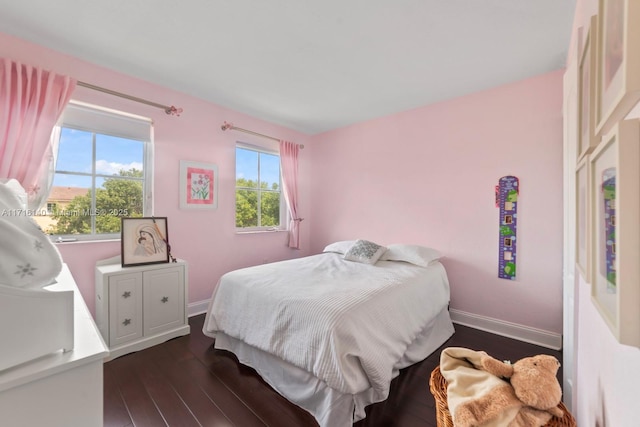 bedroom with multiple windows and dark wood-type flooring