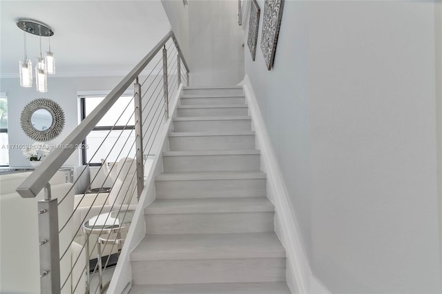 staircase featuring a notable chandelier and ornamental molding