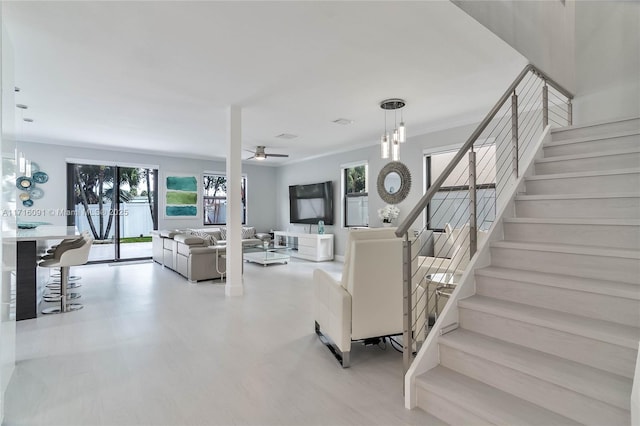 living room featuring ceiling fan with notable chandelier and crown molding