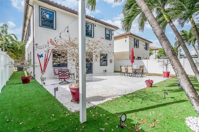 back of house featuring a patio area and a lawn