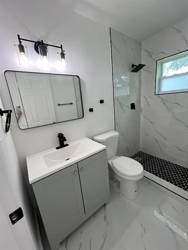 bathroom with vanity, toilet, and a tile shower