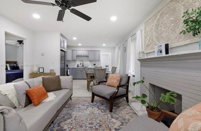 living room with ceiling fan, a fireplace, and sink