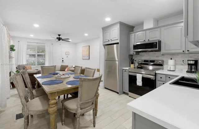 kitchen with gray cabinets, ceiling fan, appliances with stainless steel finishes, tasteful backsplash, and sink