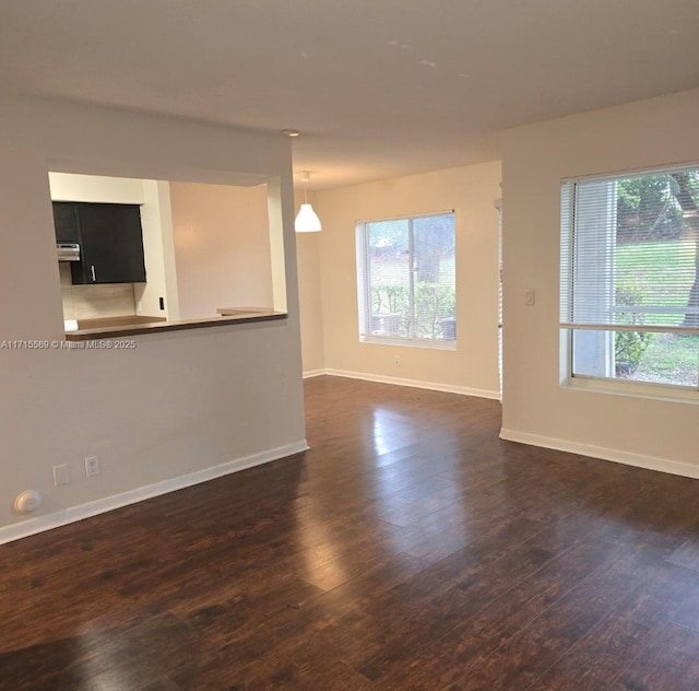 empty room featuring a healthy amount of sunlight and dark hardwood / wood-style floors