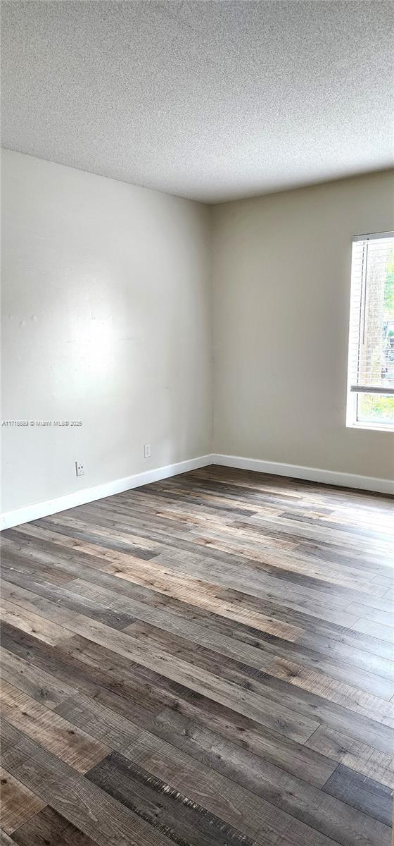 spare room with dark hardwood / wood-style floors and a textured ceiling