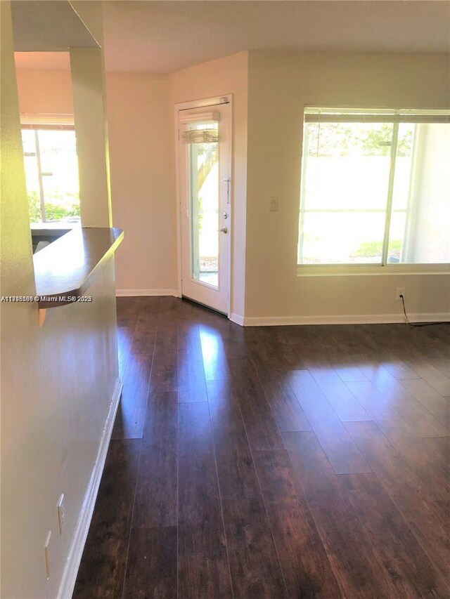 unfurnished living room featuring a healthy amount of sunlight and dark wood-type flooring