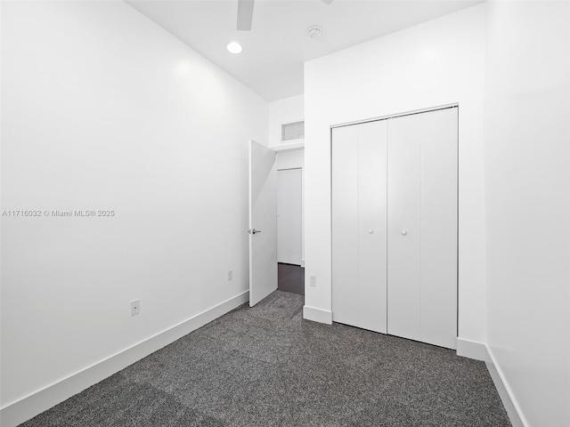 unfurnished bedroom with dark colored carpet, a closet, visible vents, and baseboards