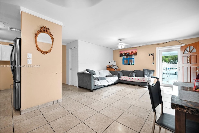 tiled living room with ceiling fan and ornamental molding