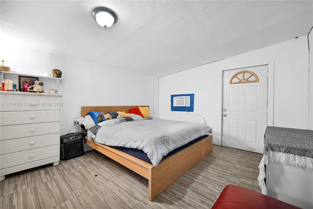 bedroom with light wood-type flooring and a wall unit AC