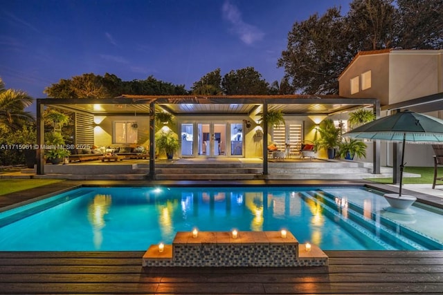 pool at dusk with french doors and a patio