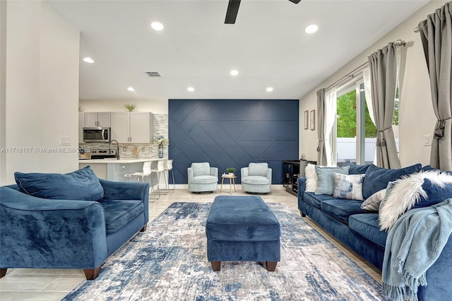 living room featuring ceiling fan, sink, and light hardwood / wood-style floors