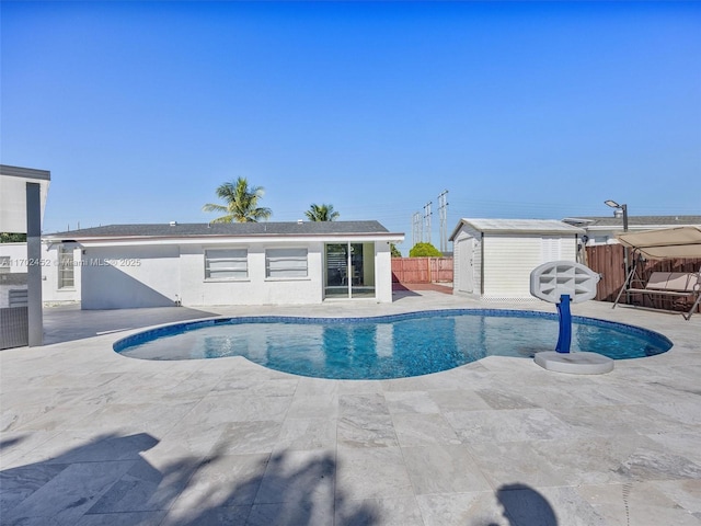 view of pool with a patio area and a shed