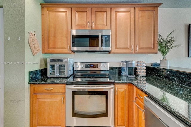 kitchen with dark stone countertops and appliances with stainless steel finishes