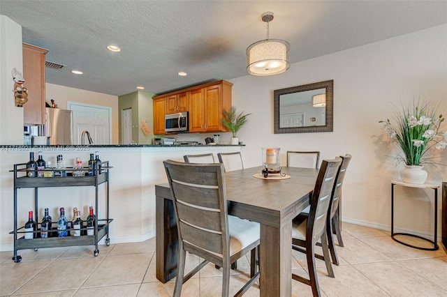 tiled dining area with sink and a textured ceiling