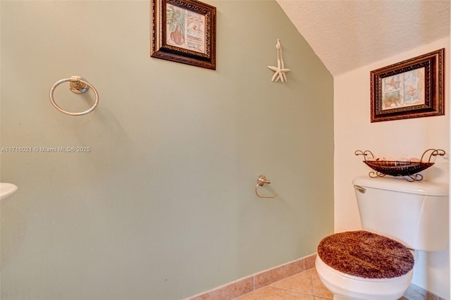 bathroom with toilet, a textured ceiling, tile patterned floors, and vaulted ceiling