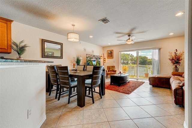 dining space featuring light tile patterned floors, a textured ceiling, and ceiling fan